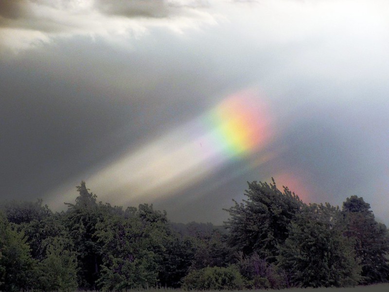 photograph of a rainbow in a cloudy sky.
